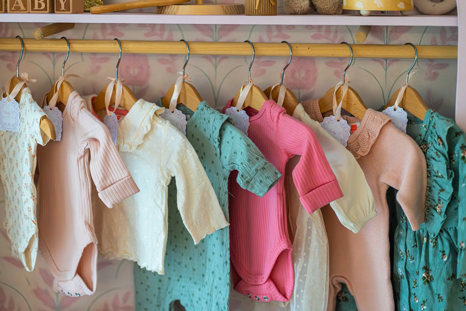 Bunte kleine Babybodys auf Holzbügeln in einem Kinderzimmer